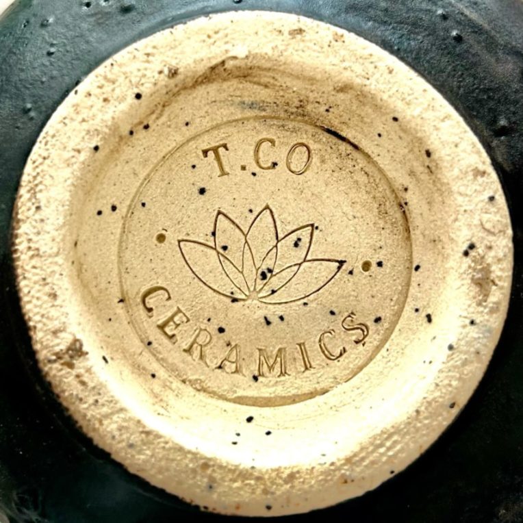 Selo T.CO Ceramics com flor de lótus carimbado no fundo de uma peça